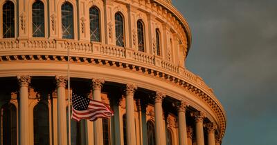 Capitol building at sunset with flag at half mast