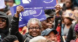 Woman holding poster above her head at Community Voices Heard rally