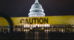 Blurry caution tape in foreground with U.S. Capitol building in background at night