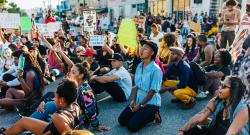 Black woman kneeling at a protest