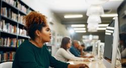 Black woman working at computer in college library