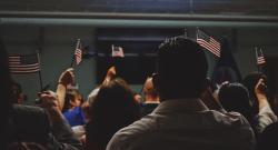 Group of people raising American flags at a naturalization ceremony