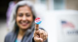 "I Voted Today" sticker on the pointer finger of a Latina woman.