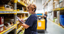 Woman warehouse worker holding clipboard, surveying inventory