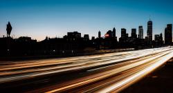 Blur of traffic light in front of backlit Manhattan skyline