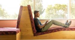 Black student reclined and working on computer