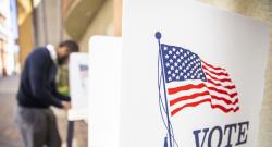 Black voter at a distance in a voting booth with an empty booth in the foreground