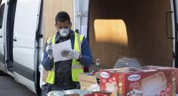 Black delivery driver with a mask on his face delivering groceries