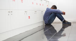 Black College Student Sitting on the Classroom Floor Looking Down in Despair