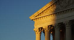 Supreme Court building cast half in light and half in shade from setting sun