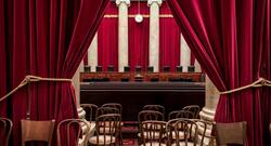 View of Supreme Court justices seats from the gallery with seats and a red curtain in foreground