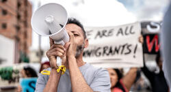 Mature man talking in a megaphone during a protest in the street