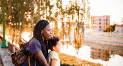 Black mother and daughter looking at the city river