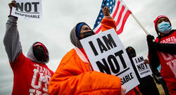 For Us Not Amazon action involving Black organizers dressed for cold weather, carrying 'I am not disposable' signs and carrying an American flag.