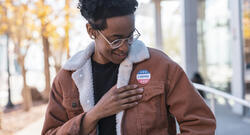 Person of color looking at their "I Voted" sticker