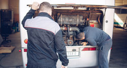 Bus manufacturer workers under the hood of a bus