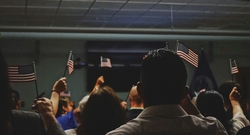 A depiction of a naturalization ceremony including a group of individuals waving flags