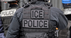 An ICE officer photographed from behind in tactical gear, with "ICE" and "ICE POLICE" patches across the back of a black vest.