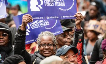 Woman holding poster above her head at Community Voices Heard rally