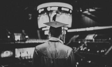 Graduate wearing cap and gown from behind in black and white