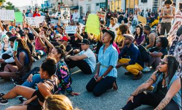 Black woman kneeling at a protest