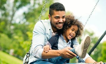Smiling Black father and child on a swing