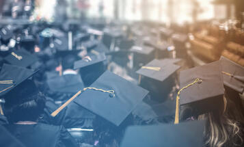 Cap and gowned students facing away at a graduation ceremony