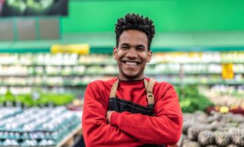 Smiling black retail worker in front of groceries