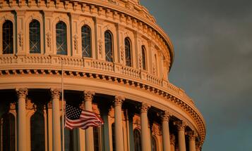 Capitol building at sunset with flag at half mast