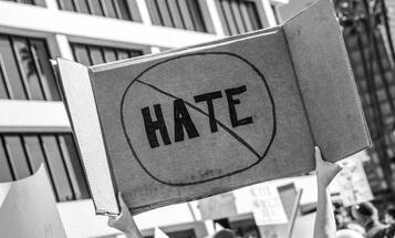 Person holding a "no hate" sign over their head