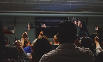 Group of people raising American flags at a naturalization ceremony