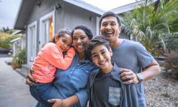 Smiling Latino family outside house