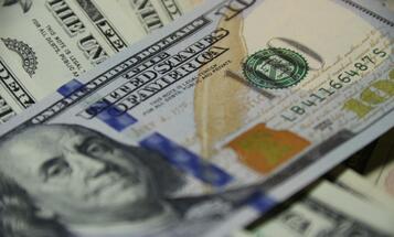 stacks of one-hundred-dollar bills with camera focus on the phrase "The United States of America"