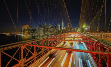 Blurred cars crossing New York City bridge at night