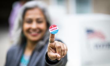 "I Voted Today" sticker on the pointer finger of a Latina woman.