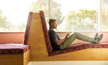 Black student reclined and working on computer