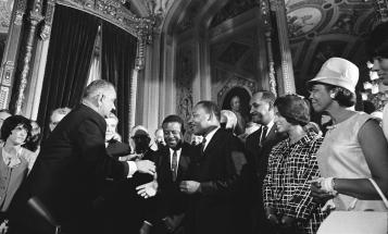 Lyndon Johnson shakes Martin Luther King, Jr.'s hand after signing the Voting Rights Act of 1965