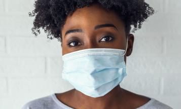 Black woman with curly hair wearing mask