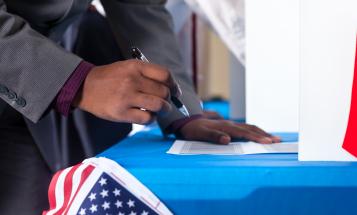 Black voter hovering over a former with a pen