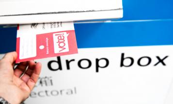 Hand dropping an absentee ballot in a drop box