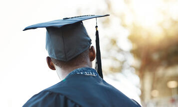 Black College Student with Cap and Gown Looking in the Distance