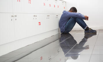 Black College Student Sitting on the Classroom Floor Looking Down in Despair