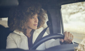 Black woman smiling, driving a car