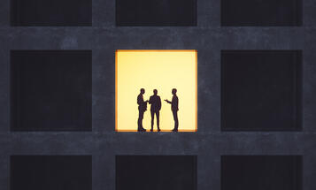 Backlit men standing in an office building window, talking