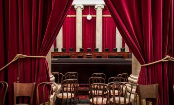 View of Supreme Court justices seats from the gallery with seats and a red curtain in foreground