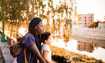 Black mother and daughter looking at the city river