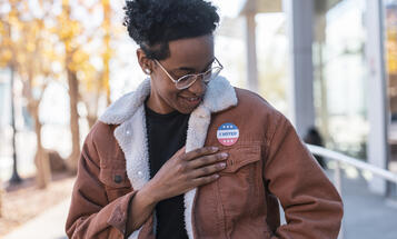 Person of color looking at their "I Voted" sticker