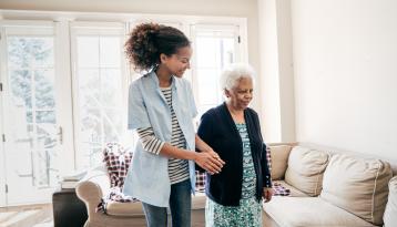 Young woman holding old woman's hand indoors