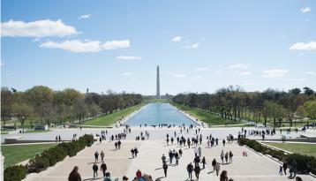 People in outdoor space with the Washington Monument in the distance