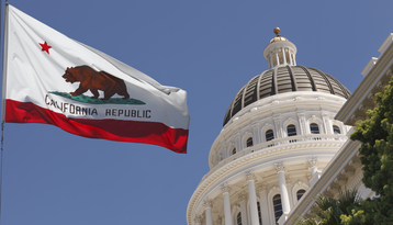 California state flag flying in front of the California State Capitol building dome, representing state-level democratic institutions and governance